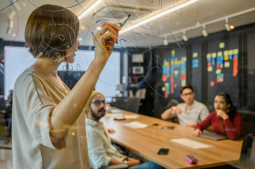 Ein Team plant gemeinsam die Umsetzung einer App auf einem Whiteboard