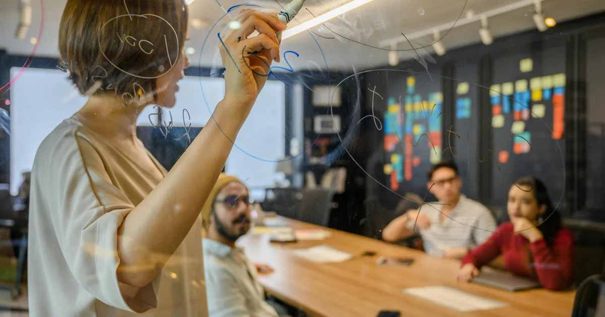 Ein Team plant gemeinsam die Umsetzung einer App auf einem Whiteboard